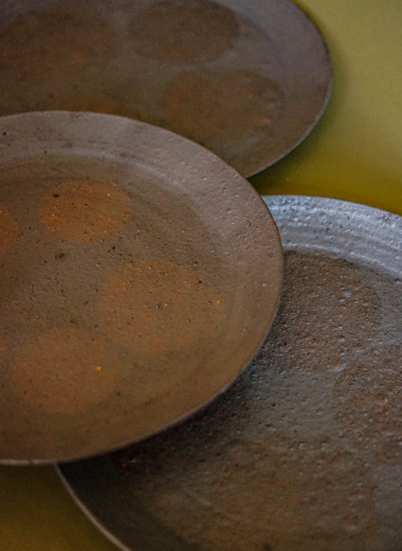 ALT=Black platters with iron resist circles in a ghostly pink. Thrown and turned by Jonathan Wade of Ingot Objects.