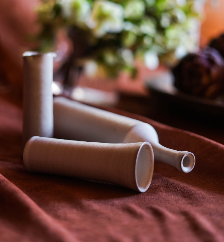 ALT=A vase, a bottle and a pourer. Shot on burgundy linen at Bard Scotland.