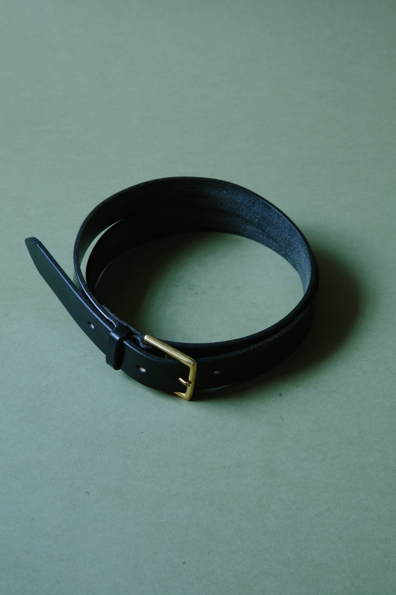 ALT=A black bridle leather belt, wrapped into a circle so it fits within frame. The metal belt is buckle can be seen.