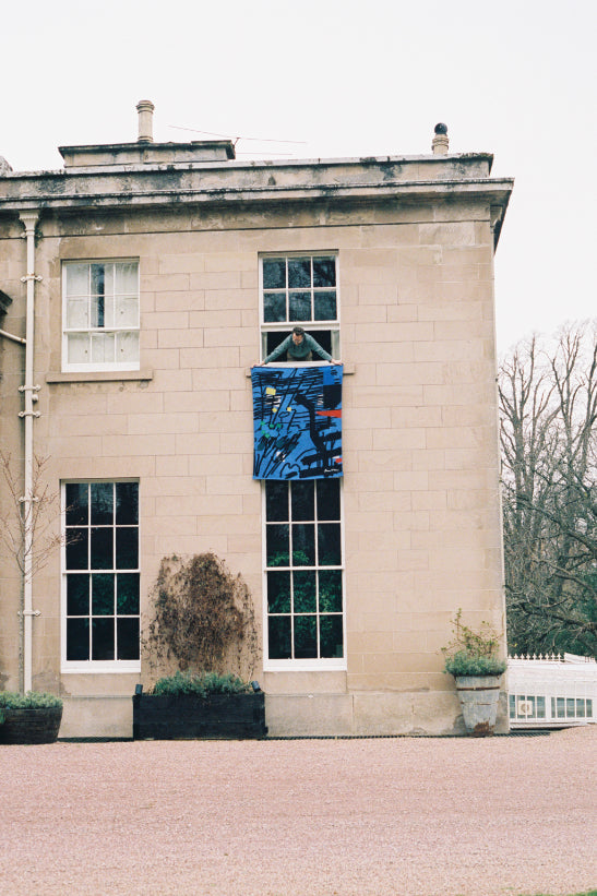 ALT=Hugo hanging the Begg X Co Bruce Mclean blanket from the window at Boath House.