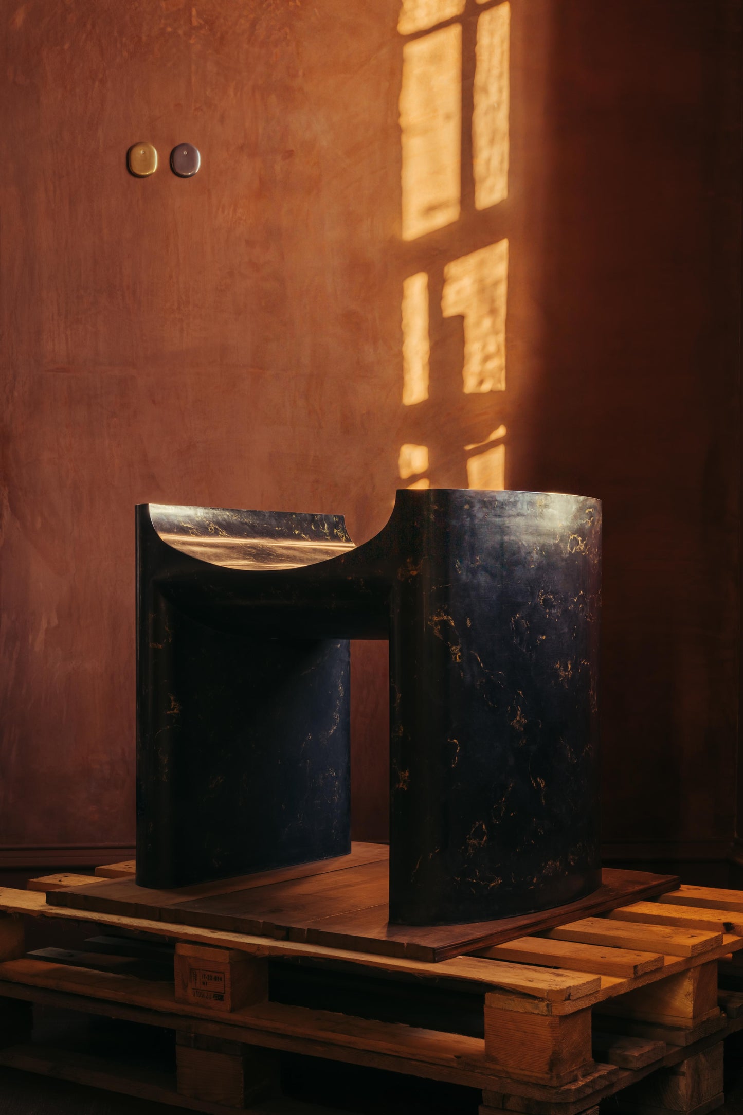 ALT= A large plaster black chair, named Cat Throne, and made by Chalk Plaster. The Throne is sat on top of a pallet as part of The Grit and The Glamour exhibition at Bard..