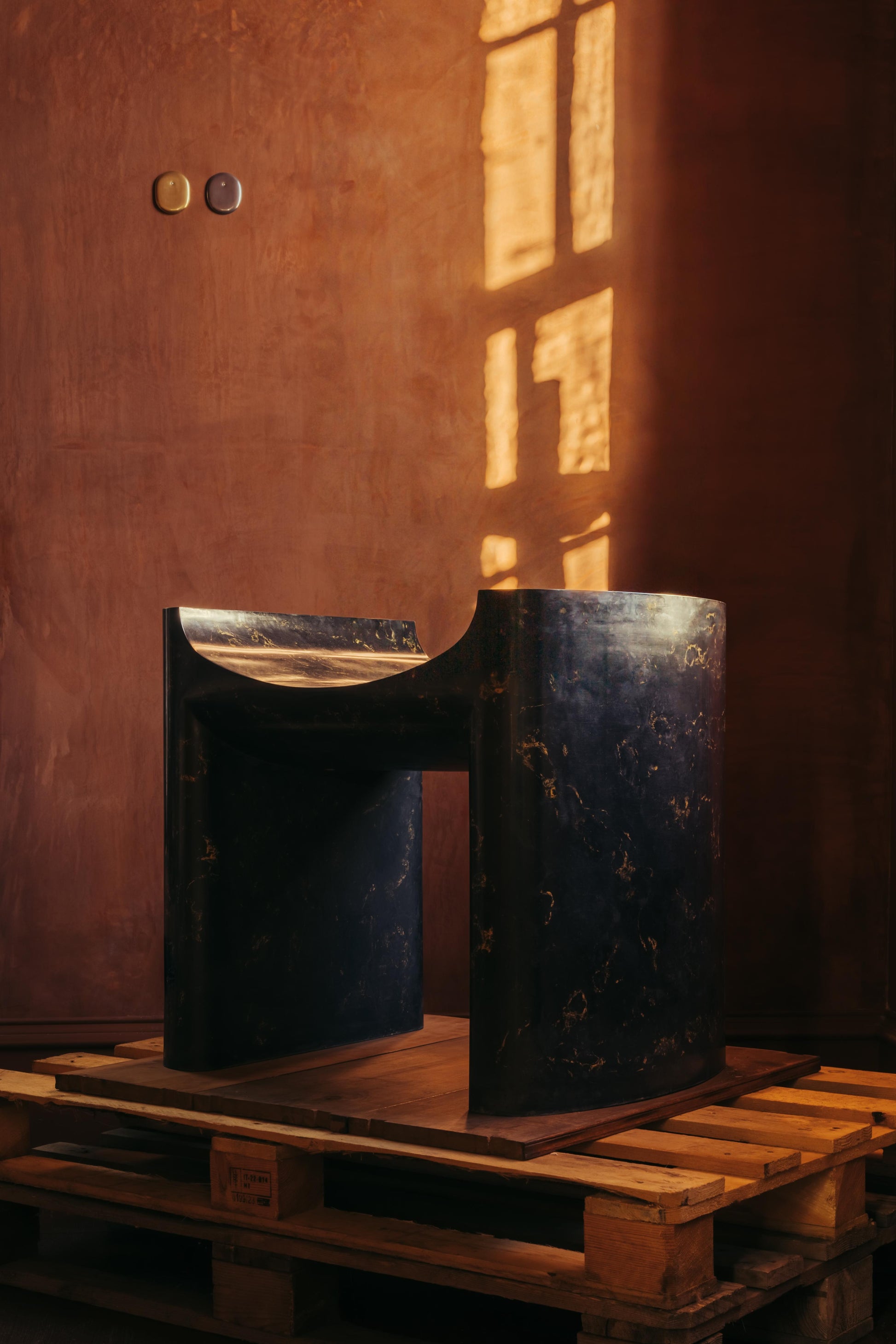 ALT= A large plaster black chair, named Cat Throne, and made by Chalk Plaster. The Throne is sat on top of a pallet as part of The Grit and The Glamour exhibition at Bard..