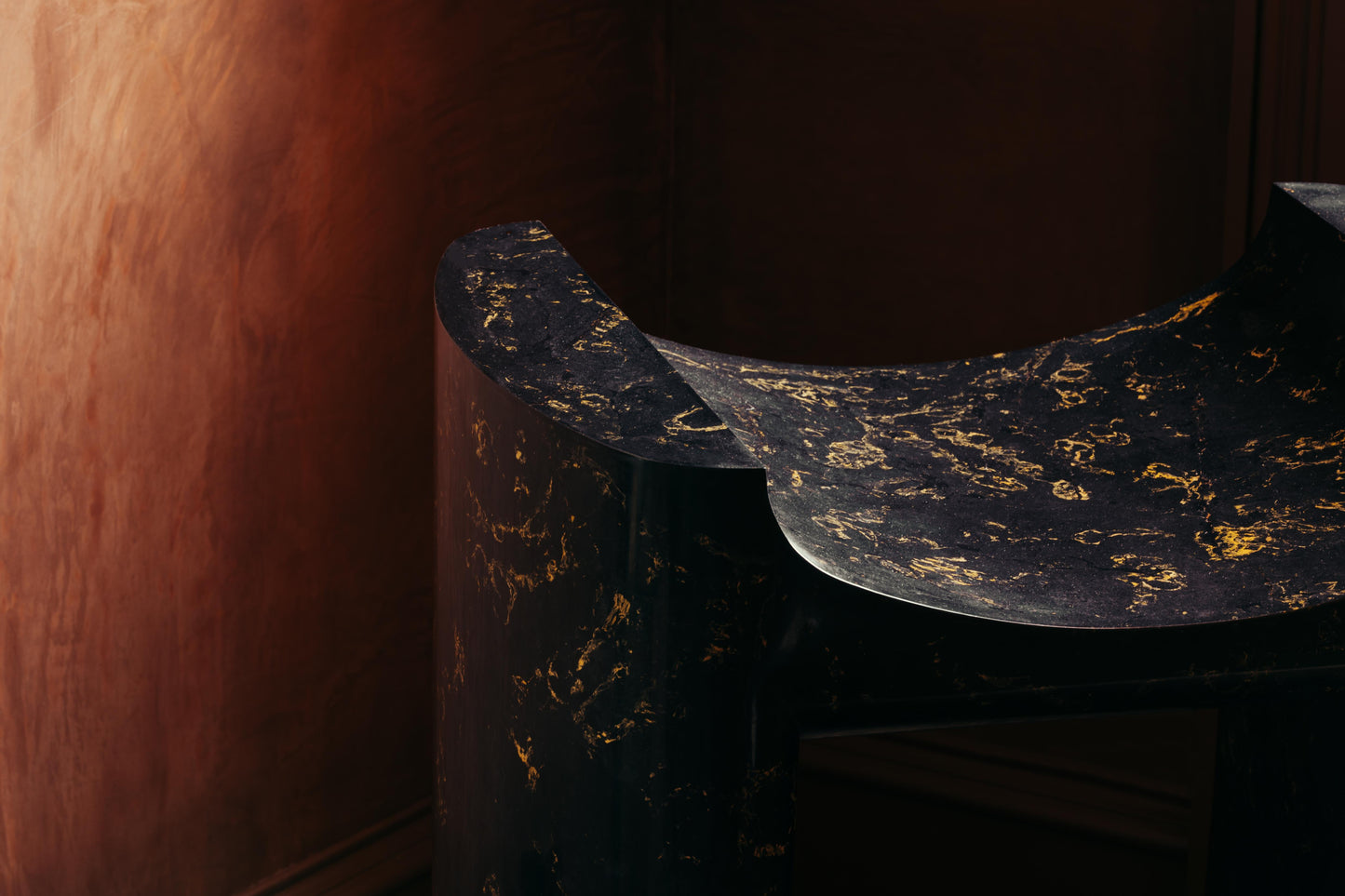 ALT= A close up shot of the Cat Throne, revealing the gold pigments mottled through the plaster cast structure. The seat has a bold shape, with pleasing curves.