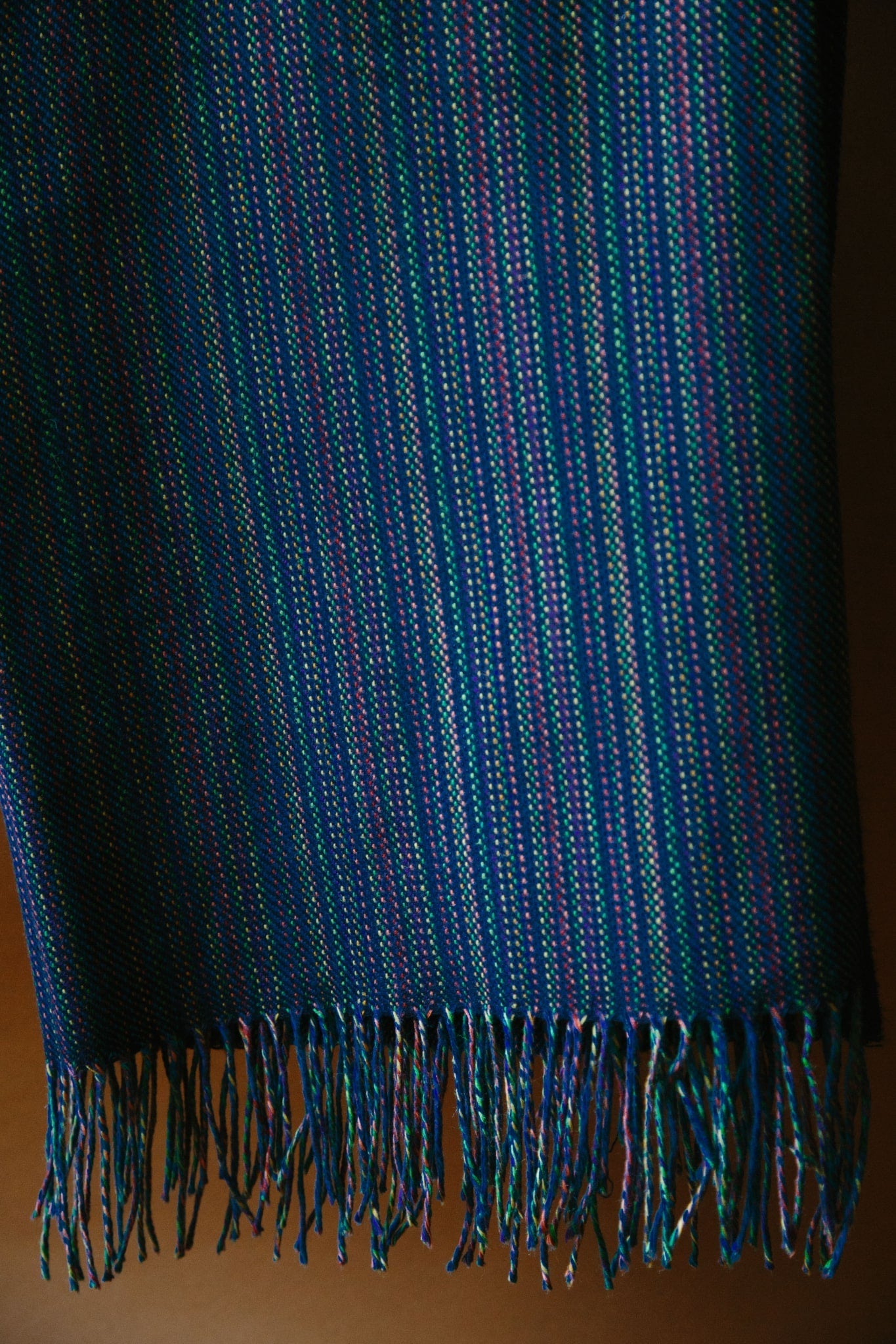 ALT=A deep navy merino throw. The shot has been taken close up so the weave structure can be seen. Multi coloured yarn has been used in the warp and a deep navy as the weft.