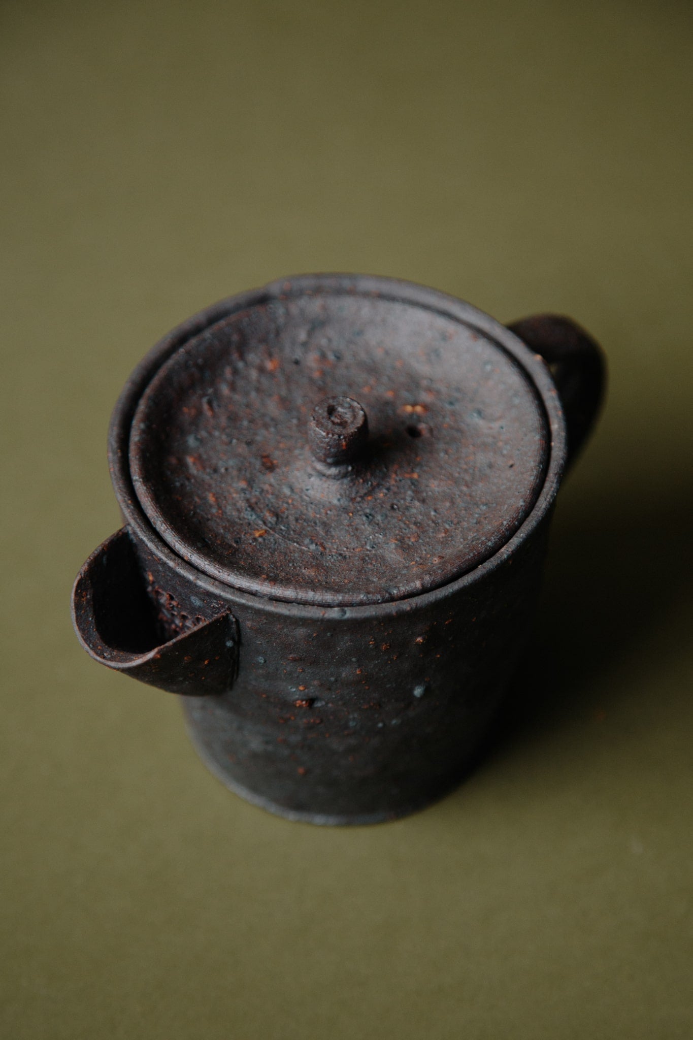 ALT=Small black ceramic teapot shot from above to see the join of the lid. The black surface is highly textured and beautifully sized for the hand.