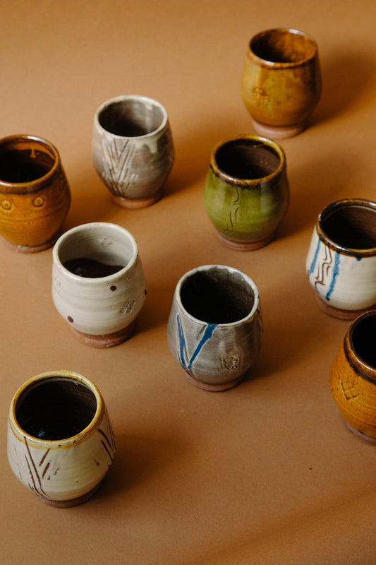 ALT=A group of nine footed drinking vessels. Each different, to show the variety produced by Joshua Williams, the studio potter who made them. 