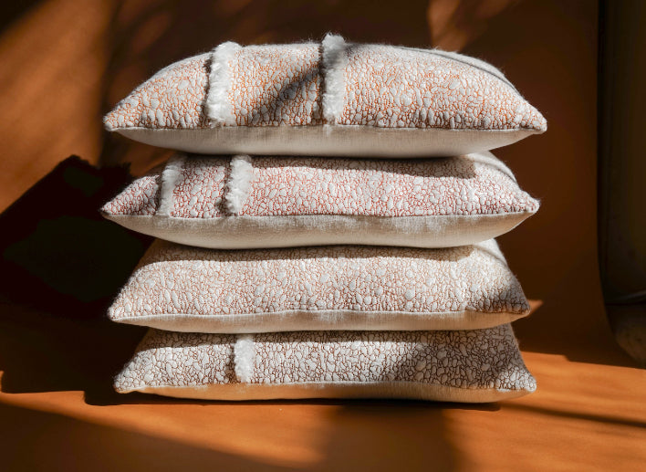 ALT=A stack of cushions by Jasmine Linington. Each unique and using SeaCell, a fibre derived from seaweed with a soft, silk-like texture and appearance. 