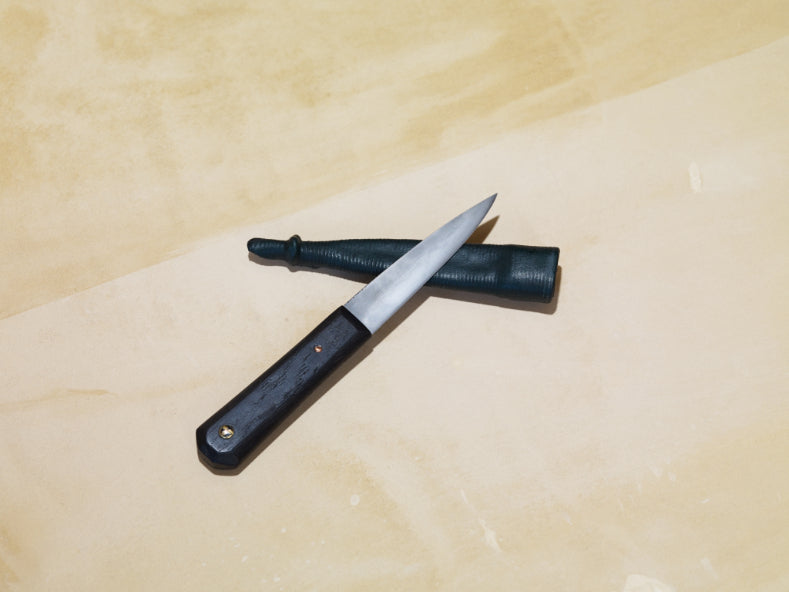 ALT= Sgian Dubh knife with a handle made from Bog Oak. Shot on a light plaster background.